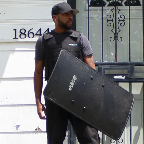 a man wearing a baseball cap while holding a handgun shield on one hand