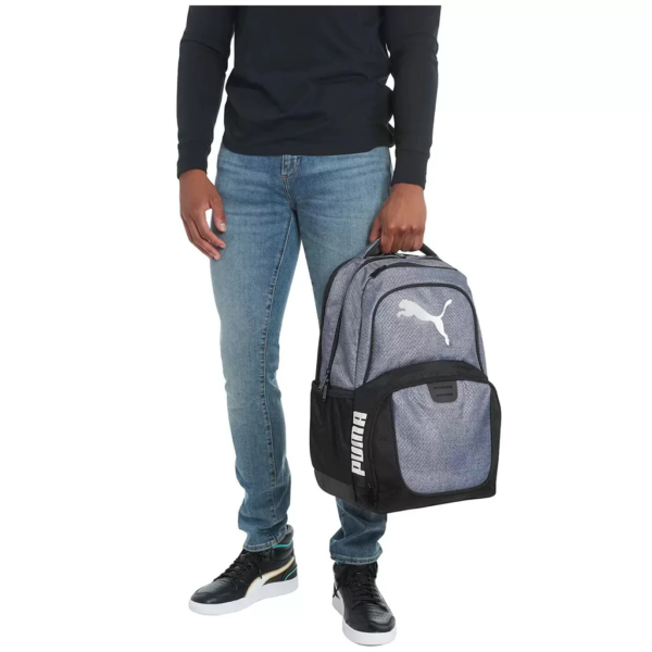 Man holding in one hand a Silver Bulletproof Puma Challenger Backpack