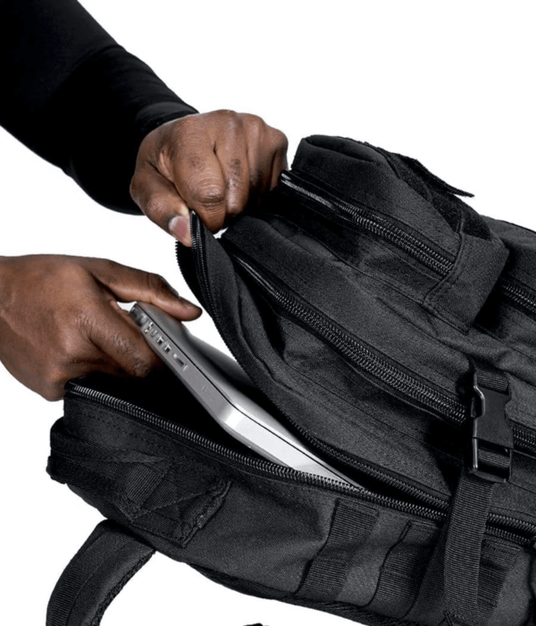 Man pulling a laptop inside a black Ultimate Assault Pack