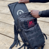 Man pulling out an item inside a Black Ultimate Assault Pack