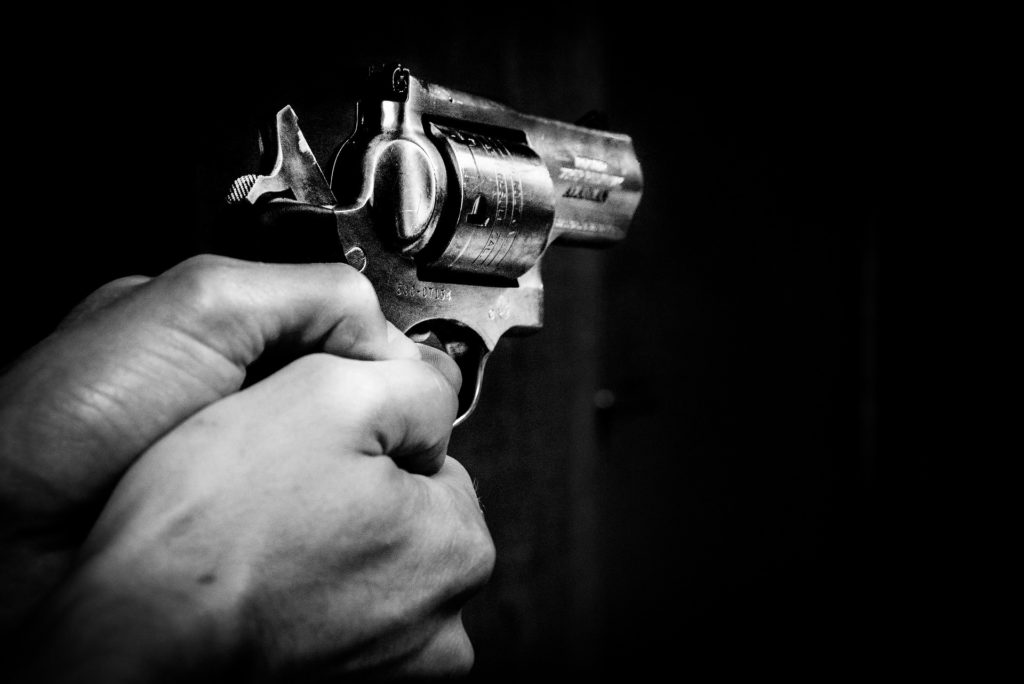 Someone holding a gun in both hands pointing it, on a black background